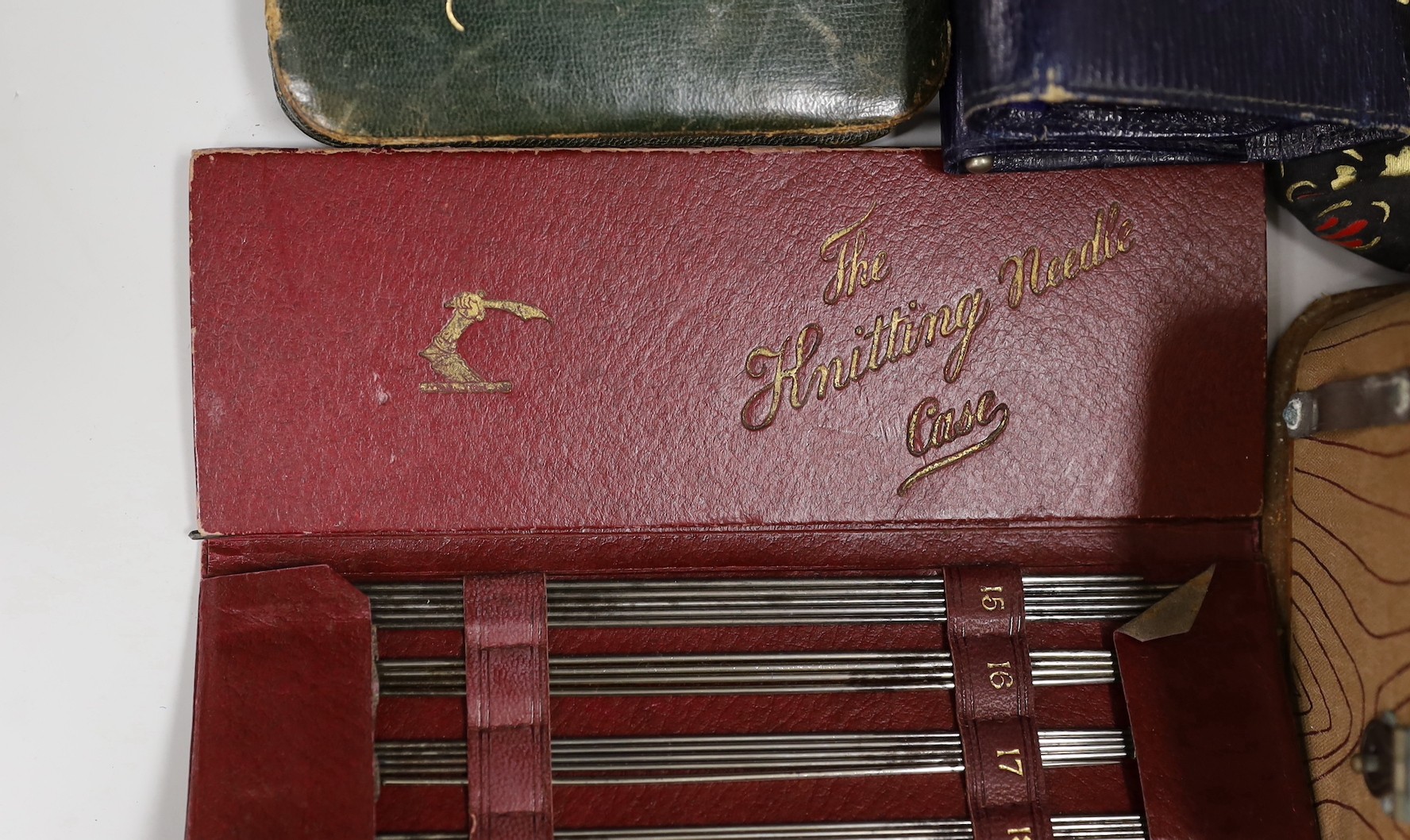 A suitcase containing a collection of late 19th century leather sewing bags and containers, wooden darning mushrooms, etc